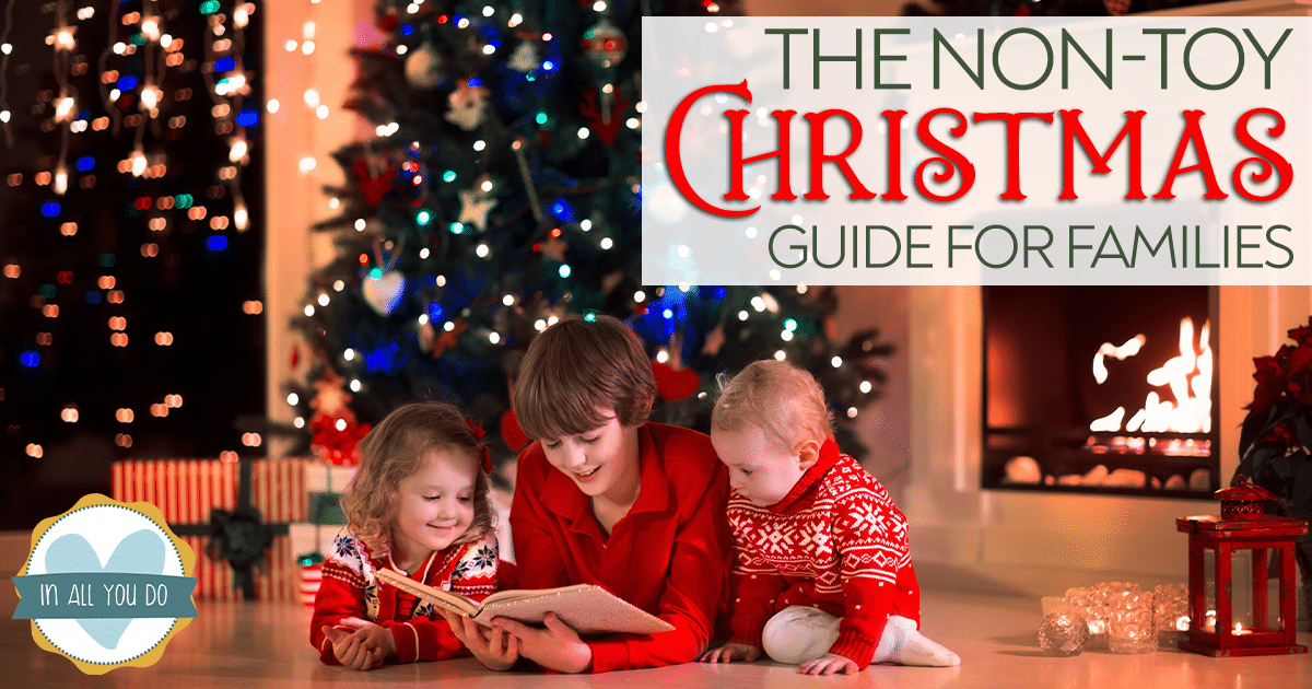 siblings reading a book in front of Christmas tree with overlay "The Non-Toy Christmas Guide for Families"