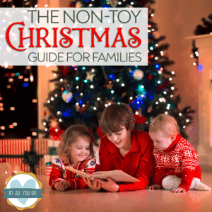 siblings reading a book in front of Christmas tree with overlay "The Non-Toy Christmas Guide for Families"